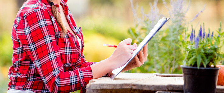 Woman writing a plan in her garden - Boston Seeds